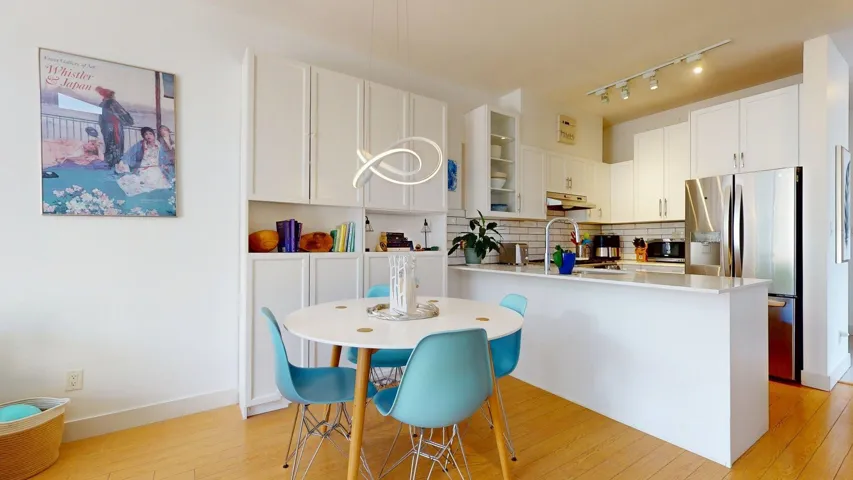 Kitchen featuring stainless steel appliances, tasteful backsplash, light wood-style flooring, light countertops, and white cabinetry