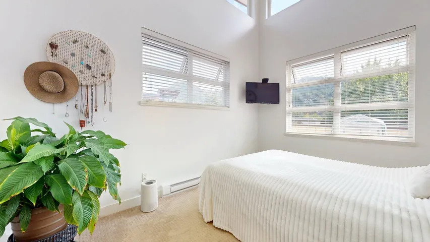 Bedroom with baseboard heating and light carpet