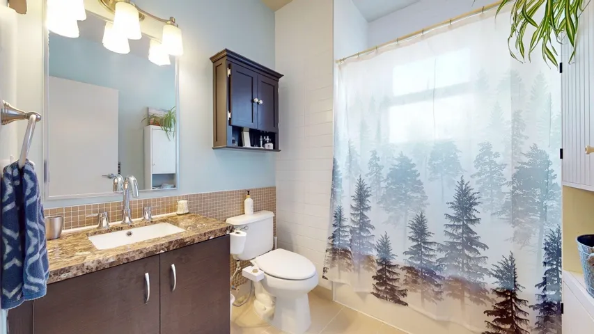 Bathroom featuring tile walls, tile patterned flooring, vanity, and a wainscoted wall