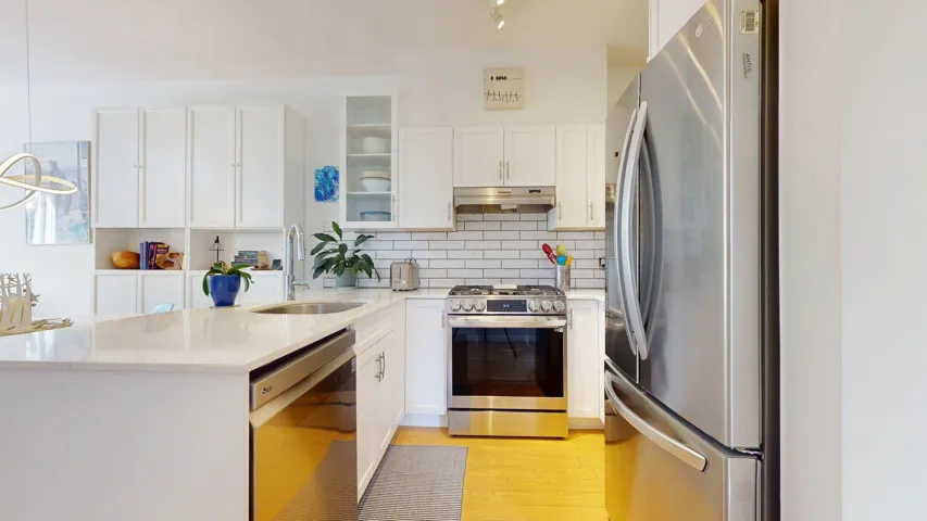 Kitchen with appliances with stainless steel finishes, tasteful backsplash, white cabinetry, and glass insert cabinets