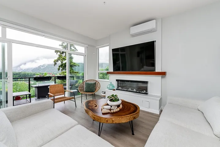 Living area featuring an AC wall unit, wood finished floors, and a glass covered fireplace