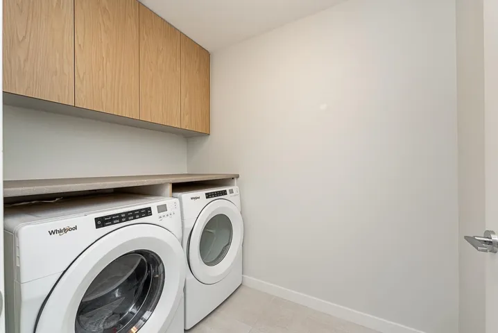 Laundry area with cabinet space, washing machine and clothes dryer, baseboards, and light tile patterned floors
