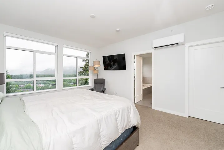 Bedroom with an AC wall unit, carpet, baseboards, and ensuite bathroom