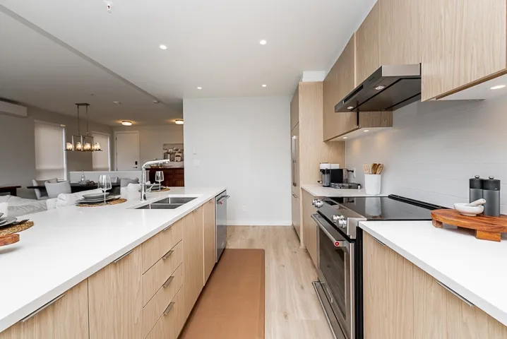 Kitchen with appliances with stainless steel finishes, a sink, light brown cabinetry, range hood, and modern cabinets