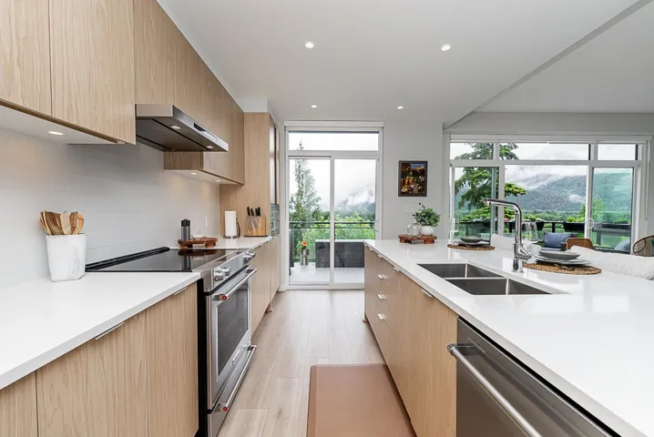 Kitchen featuring exhaust hood, a sink, appliances with stainless steel finishes, modern cabinets, and light countertops