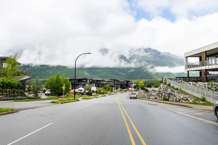 View of asphalt road featuring street lighting, curbs, a mountain view, and sidewalks