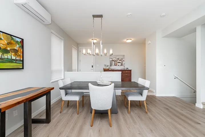 Dining room with a wall mounted AC, light wood-style flooring, and baseboards