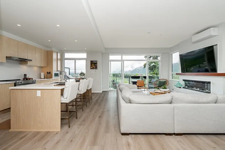 Living room with a wall mounted air conditioner, light wood finished floors, a glass covered fireplace, and recessed lighting