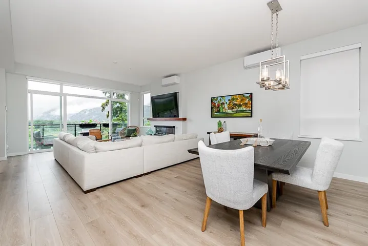 Dining area with light wood-style floors, a wall mounted air conditioner, a chandelier, and a glass covered fireplace