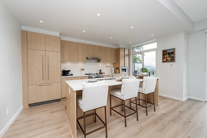 Kitchen with modern cabinets, light wood-style flooring, a kitchen bar, light countertops, and recessed lighting