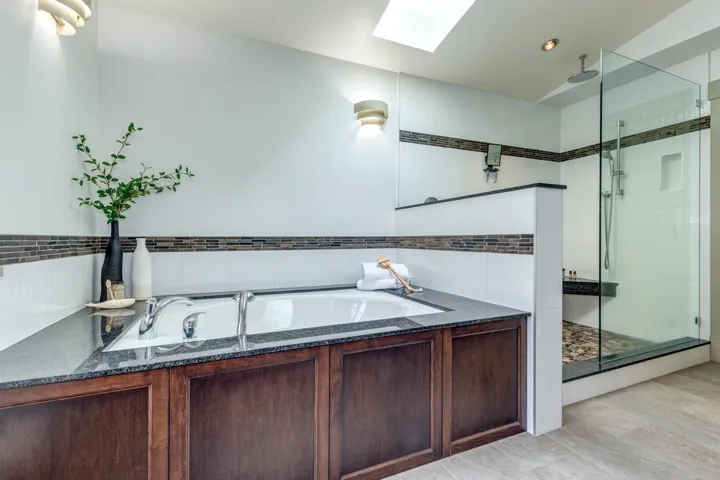 Soaking tub with a dark stone surround and wood-finish paneling