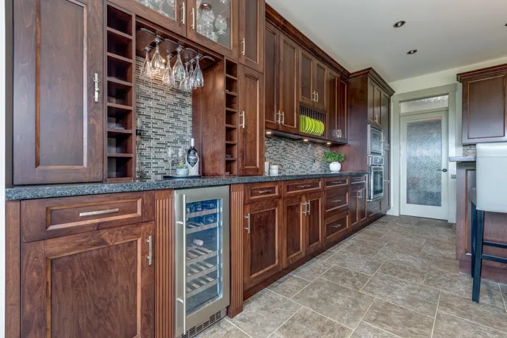 Custom cabinetry featuring a built-in wine rack, glass-front display cabinets, and an under-counter beverage refrigerator