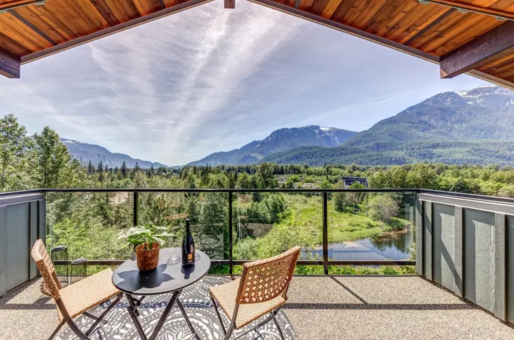 Spacious balcony featuring glass railings, exposed aggregate flooring, and a natural wood-finish ceiling