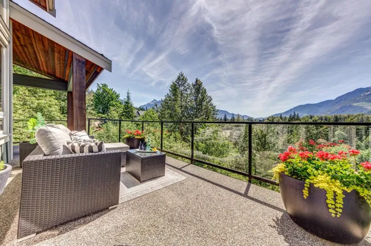 Outdoor balcony featuring a glass railing system and exposed aggregate concrete flooring