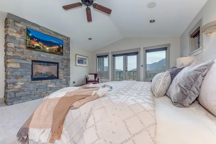 Vaulted ceiling room featuring a stone-clad fireplace and wood-blade ceiling fan