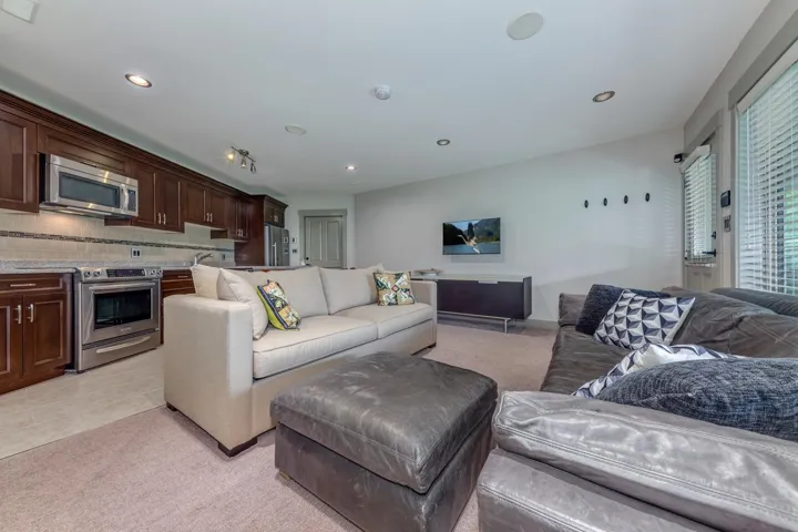 Open concept living space featuring a full kitchen with dark wood cabinetry, stainless steel appliances, and a tiled backsplash