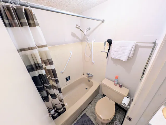 Bathroom with shower / bath combination with curtain and a textured ceiling