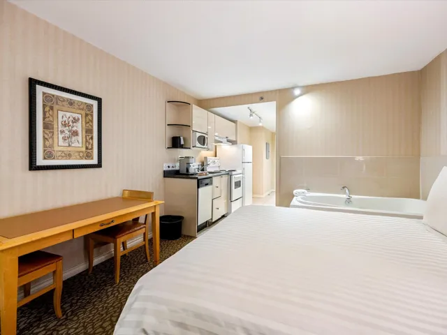 Bedroom with wallpapered walls and dark colored carpet