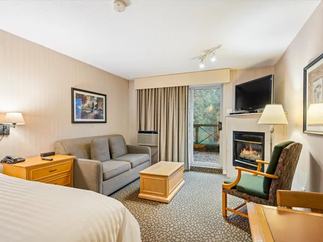 Carpeted bedroom with wallpapered walls, a tiled fireplace, and access to outside