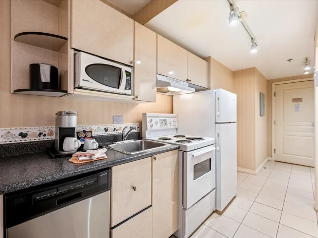 Kitchen featuring white appliances, open shelves, under cabinet range hood, rail lighting, and dark countertops
