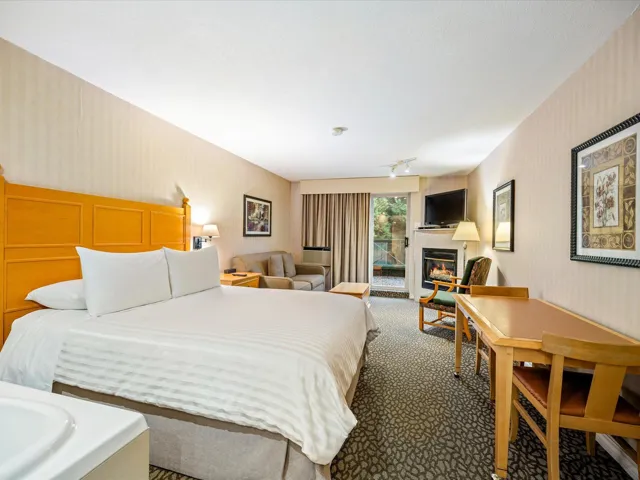 Carpeted bedroom with wallpapered walls, access to exterior, and a glass covered fireplace