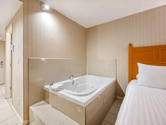 Full bath with wallpapered walls, a jetted tub, and light tile patterned flooring