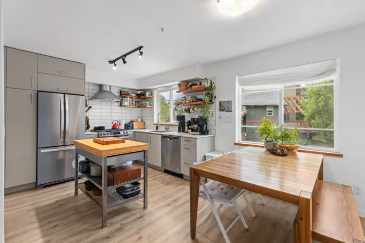 Kitchen featuring appliances with stainless steel finishes, gray cabinets, open shelves, light wood-style floors, and backsplash