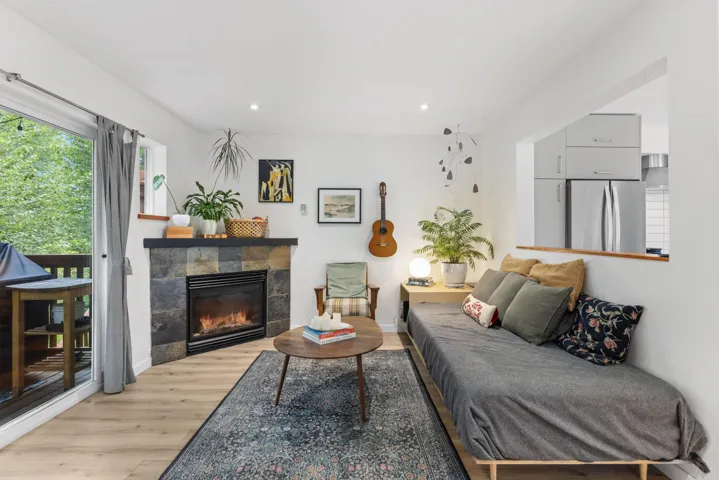 Living area with light wood finished floors, a tiled fireplace, and recessed lighting