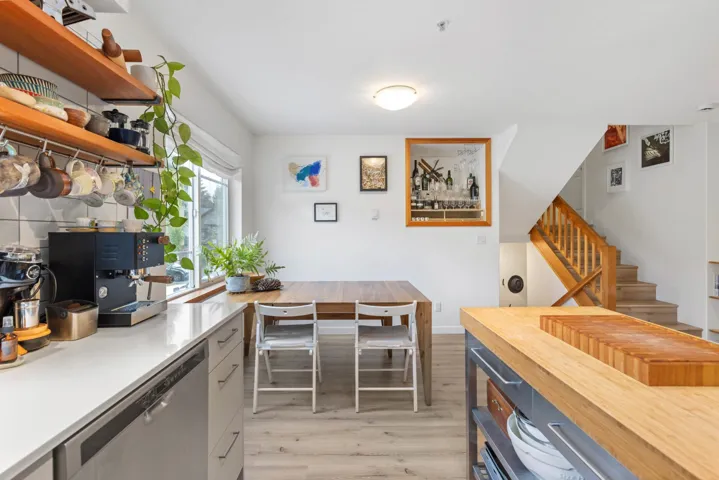 Kitchen with stainless steel dishwasher, light wood-style floors, and open shelves