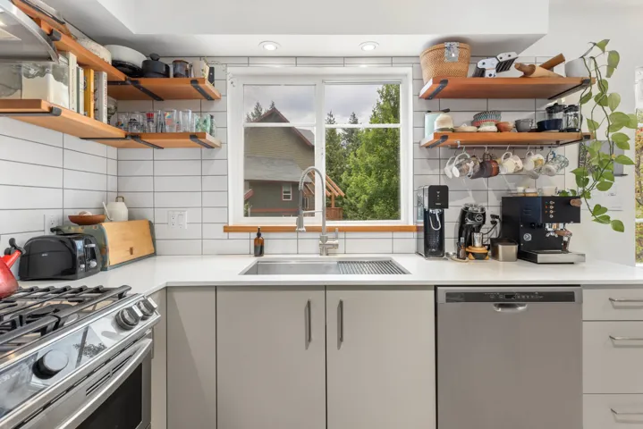 Kitchen with stainless steel appliances, open shelves, decorative backsplash, and light countertops