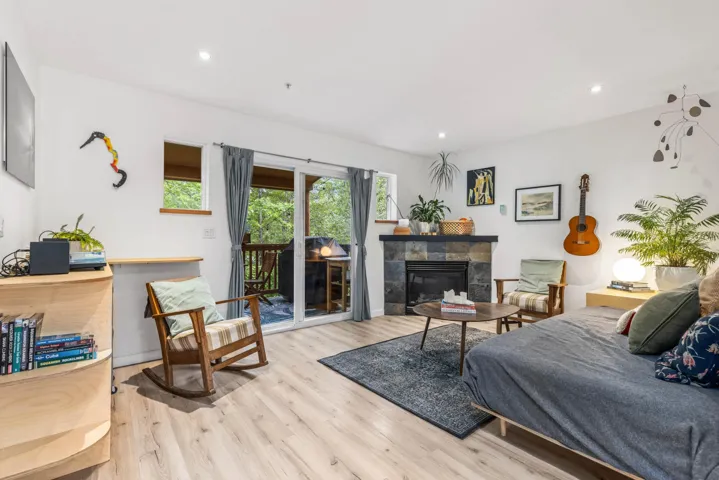 Bedroom with access to exterior, wood finished floors, a glass covered fireplace, and recessed lighting