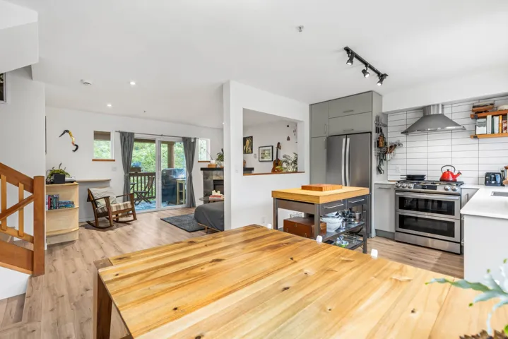 Dining area with light wood finished floors, stairs, track lighting, and a stone fireplace