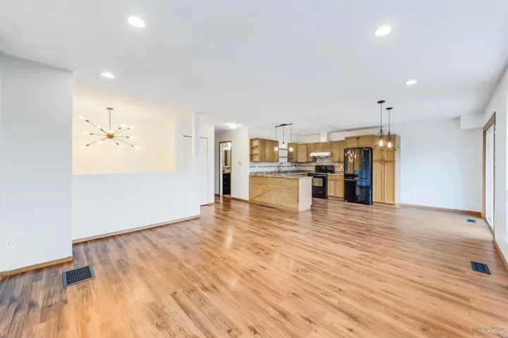 Unfurnished living room featuring recessed lighting, light wood-style floors, visible vents, and an inviting chandelier