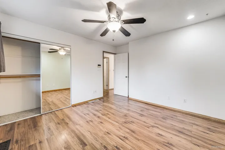 Unfurnished bedroom with a closet, a ceiling fan, visible vents, wood finished floors, and baseboards
