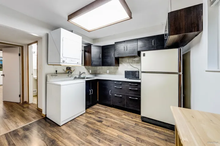 Kitchen featuring freestanding refrigerator, wood finished floors, light countertops, a sink, and decorative backsplash