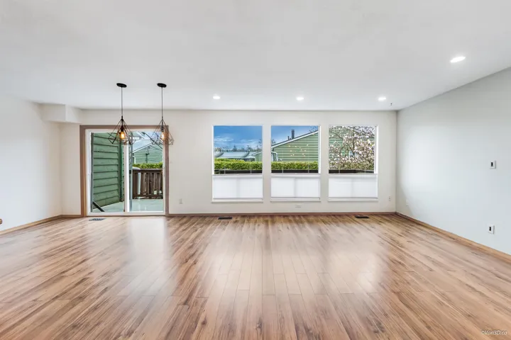 Unfurnished living room with a chandelier, wood finished floors, baseboards, and recessed lighting