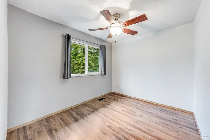 Empty room featuring visible vents, baseboards, a ceiling fan, and wood finished floors