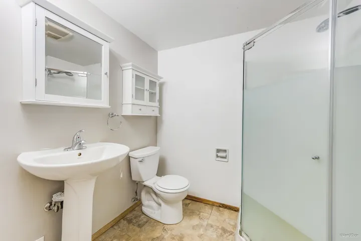 Bathroom with a shower stall, a sink, baseboards, and toilet