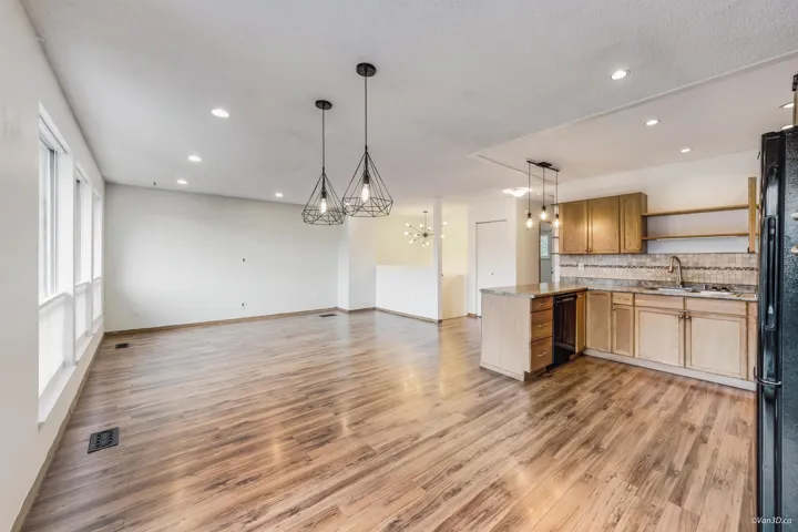 Kitchen with an inviting chandelier, freestanding refrigerator, a peninsula, open shelves, and a sink