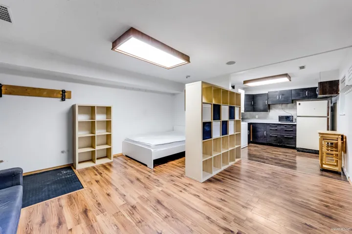 Bedroom with light wood-type flooring, freestanding refrigerator, baseboards, and visible vents