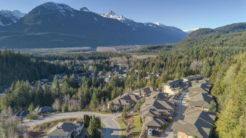 Residential community nestled within a forested valley, featuring a mountainous backdrop