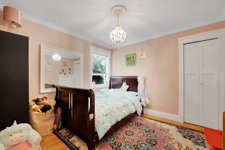 Bedroom with light wood finished floors, ornamental molding, a chandelier, and a closet