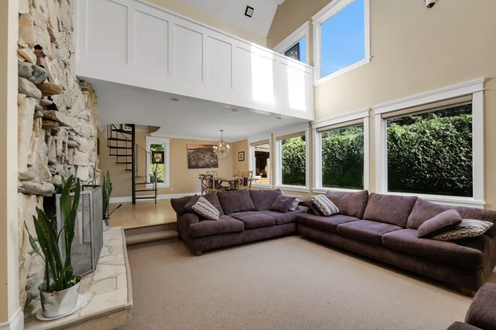 Living area featuring a high ceiling, carpet, a fireplace, a chandelier, and stairs