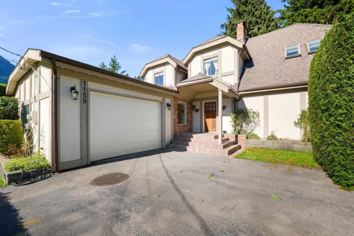 View of front of home with stucco siding, a chimney, asphalt driveway, and an attached garage