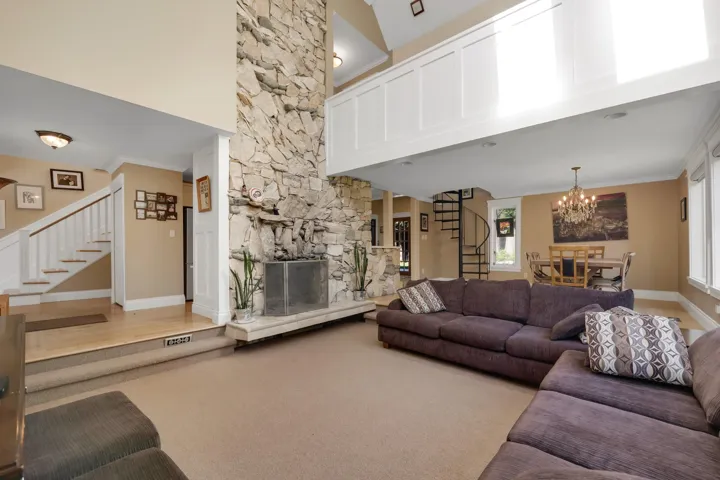 Living room featuring stairway, ornamental molding, a fireplace, a chandelier, and a high ceiling