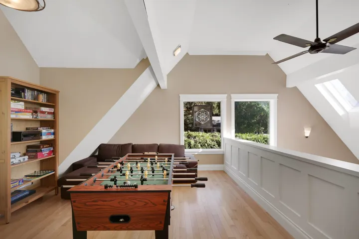 Rec room with a skylight, light wood-style floors, vaulted ceiling, and ceiling fan