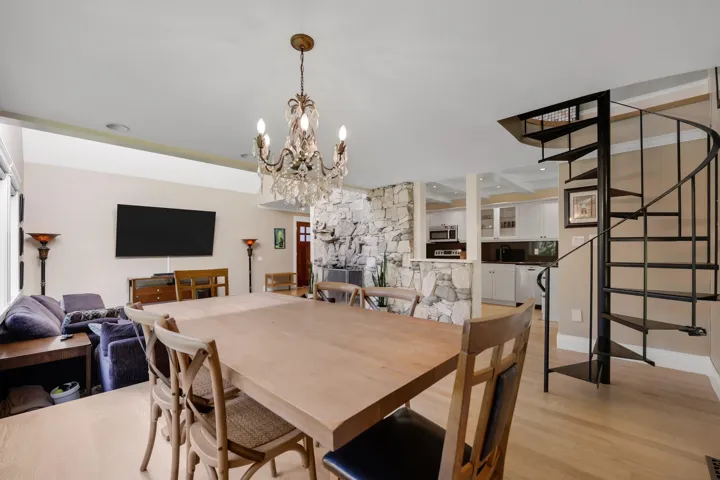 Dining room with stairs, light wood-style floors, and a chandelier
