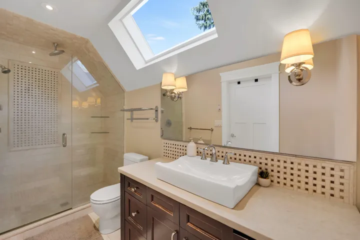 Full bath with a stall shower, tasteful backsplash, vanity, a skylight, and lofted ceiling