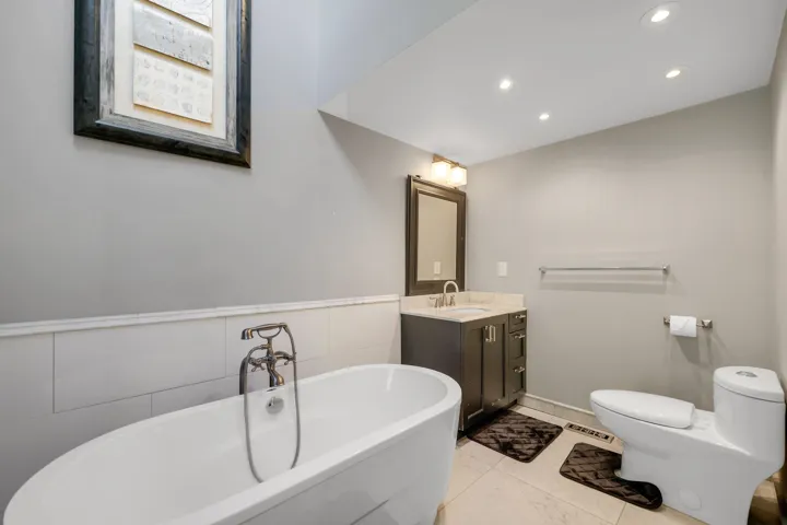 Bathroom featuring a freestanding tub, vanity, recessed lighting, light tile patterned flooring, and tile walls
