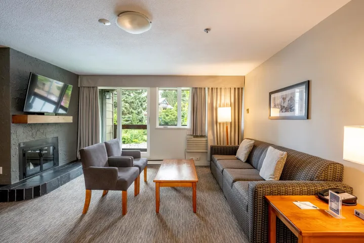 Carpeted living room featuring a tiled fireplace and a baseboard radiator